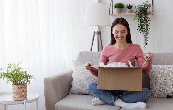 woman opening a parcel on the sofa. flexible data cleansing and address validation services